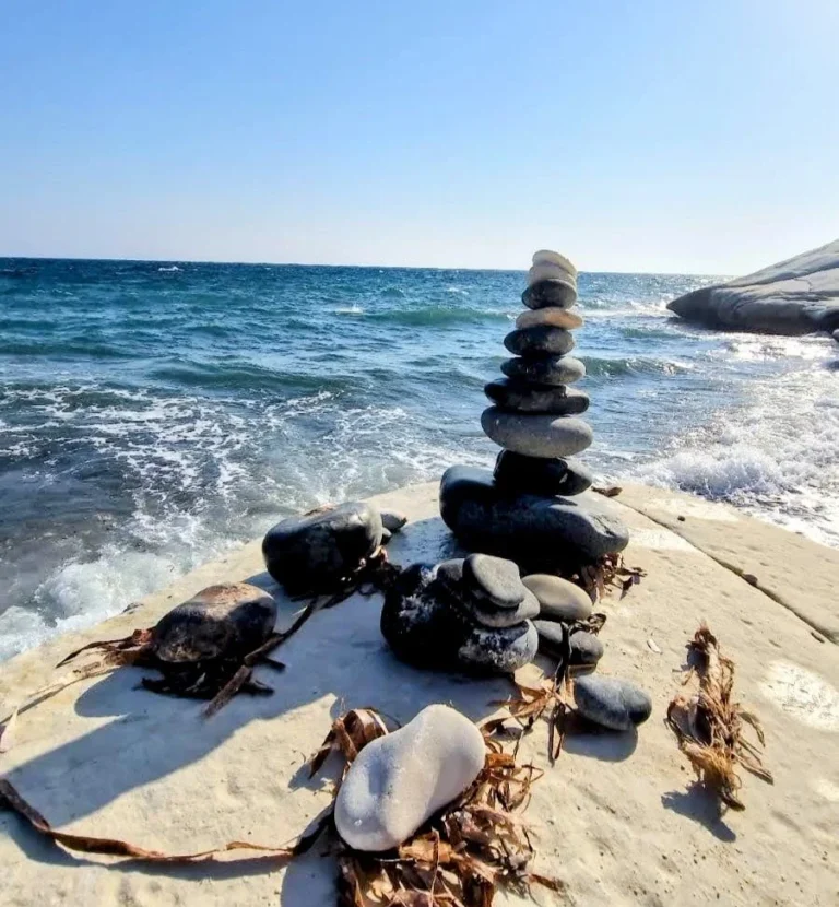 Stacked rocks by the sea symbolizing balance and grounding at healing retreat in Cyprus